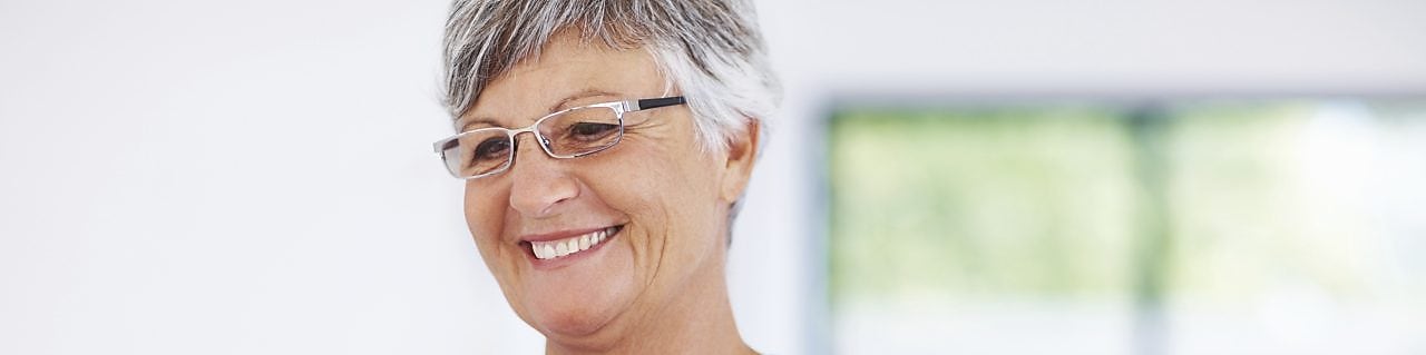 Smiling lady with cup of drink looking at her computer screen