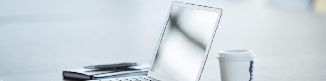 A Laptop, mobile and Coffee mug at desk